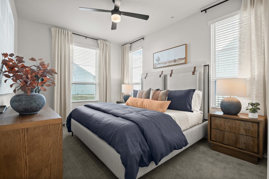 A bedroom with a bed, nightstands, and a ceiling fan.