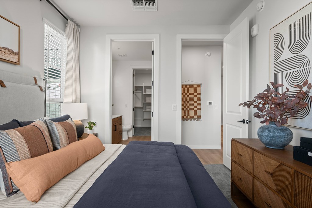 A bedroom with a bed, a dresser, and a painting on the wall.