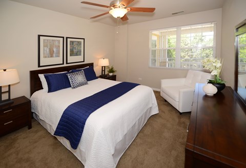 A bedroom with a large bed and a ceiling fan.