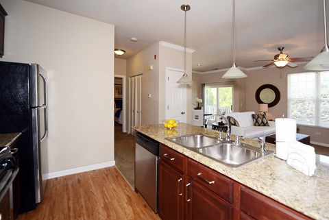 A kitchen with a black refrigerator and wooden floors.