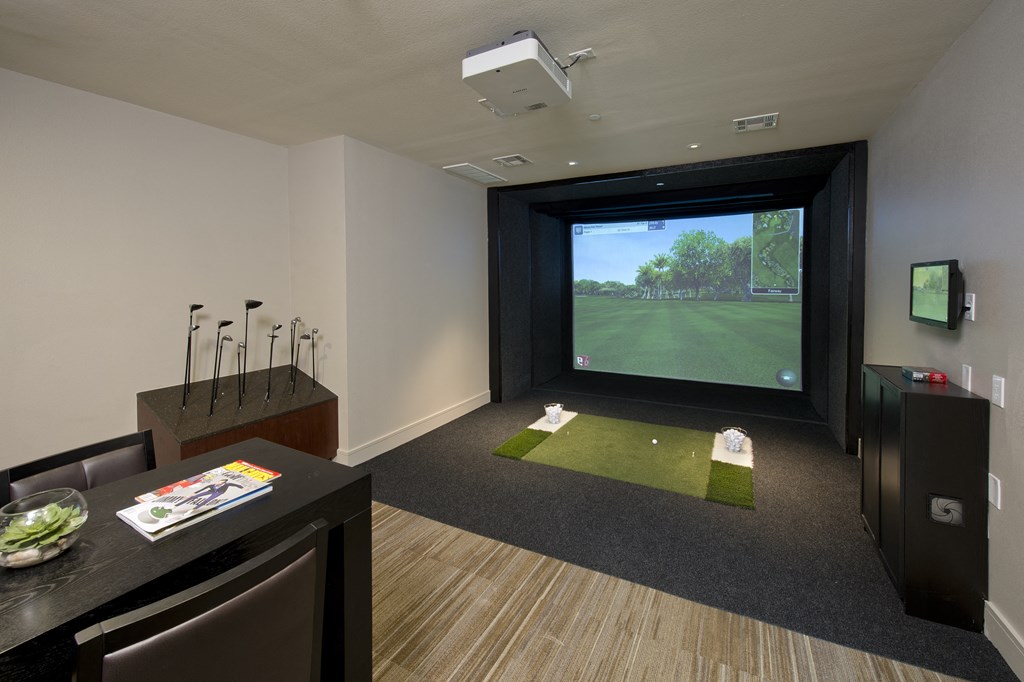 a living room with a golf simulator and a view of a putting green