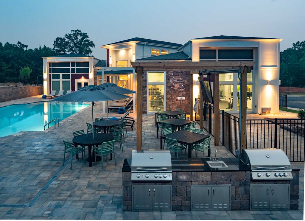 a backyard with a pool and patio with a grill and dining area
