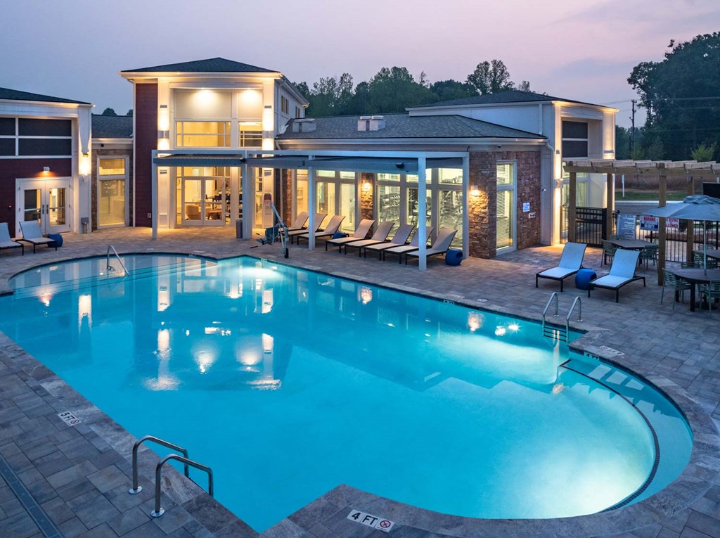 a swimming pool with lounge chairs and a building in the background