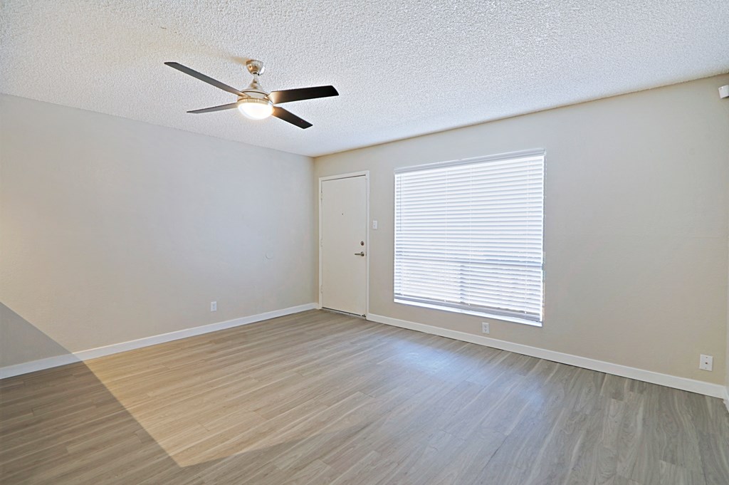 an empty bedroom with a large window and a ceiling fan
