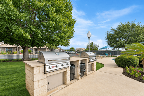 A BBQ grill is on a stand in a backyard.