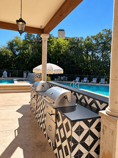 A poolside area with a black and white tiled bar and a pool in the background.