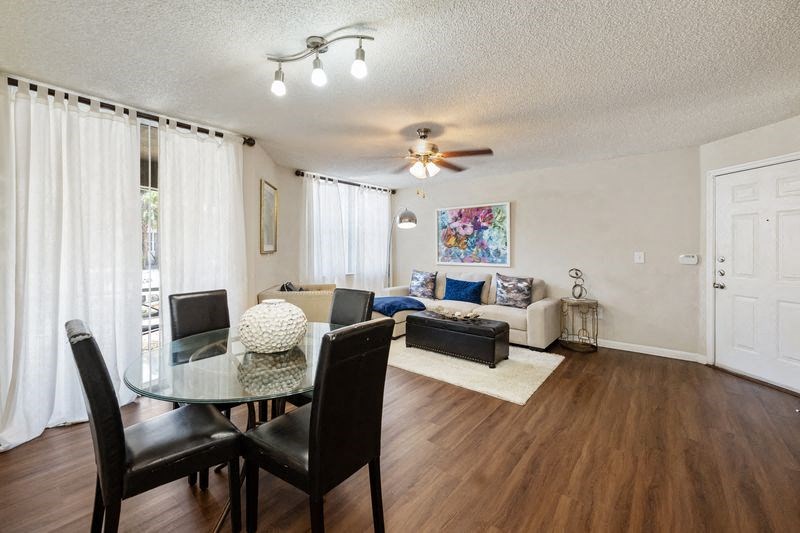 a living room and dining room with a table and a ceiling fan