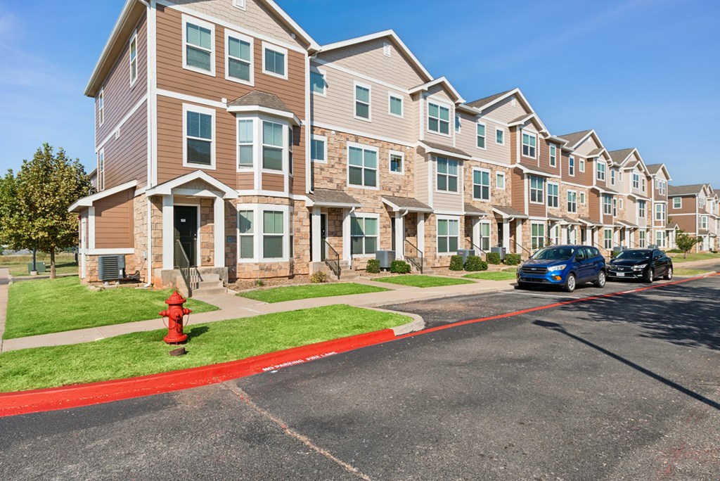 A row of apartment buildings with a red fire hydrant in front of the first one.