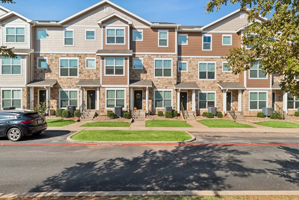 A black car is parked on the side of a road in front of a building.