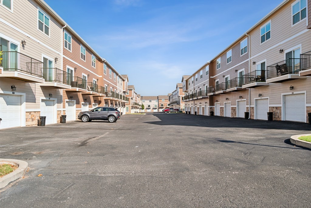 A car is parked in a parking lot in front of apartment buildings.
