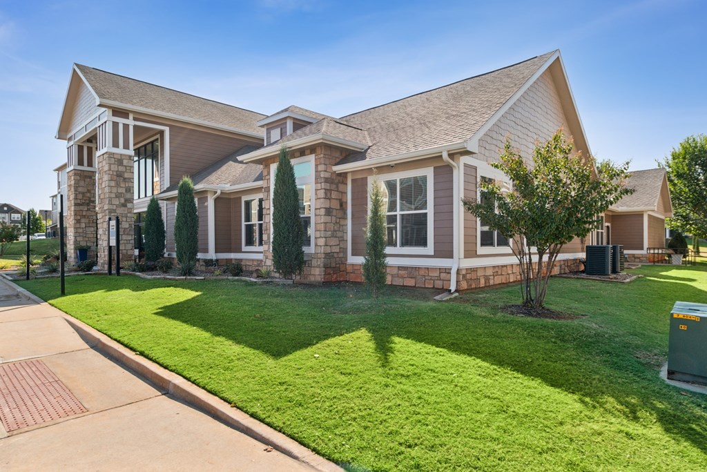 A house with a brown roof and a green lawn in front.