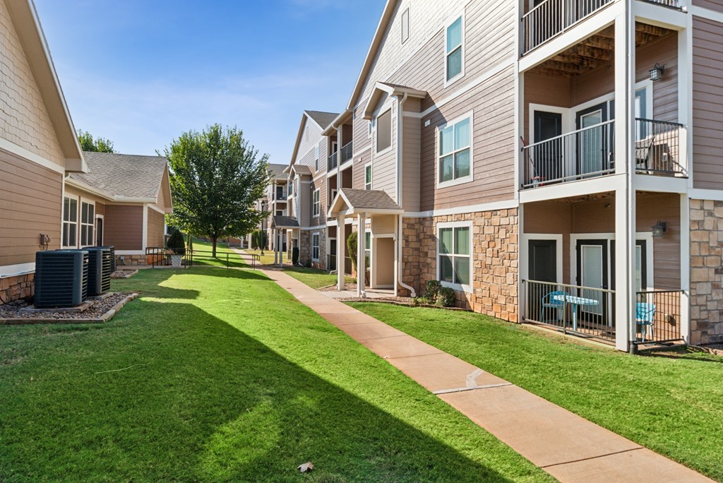 A sunny day at a residential apartment complex with a well-maintained lawn and pathway.