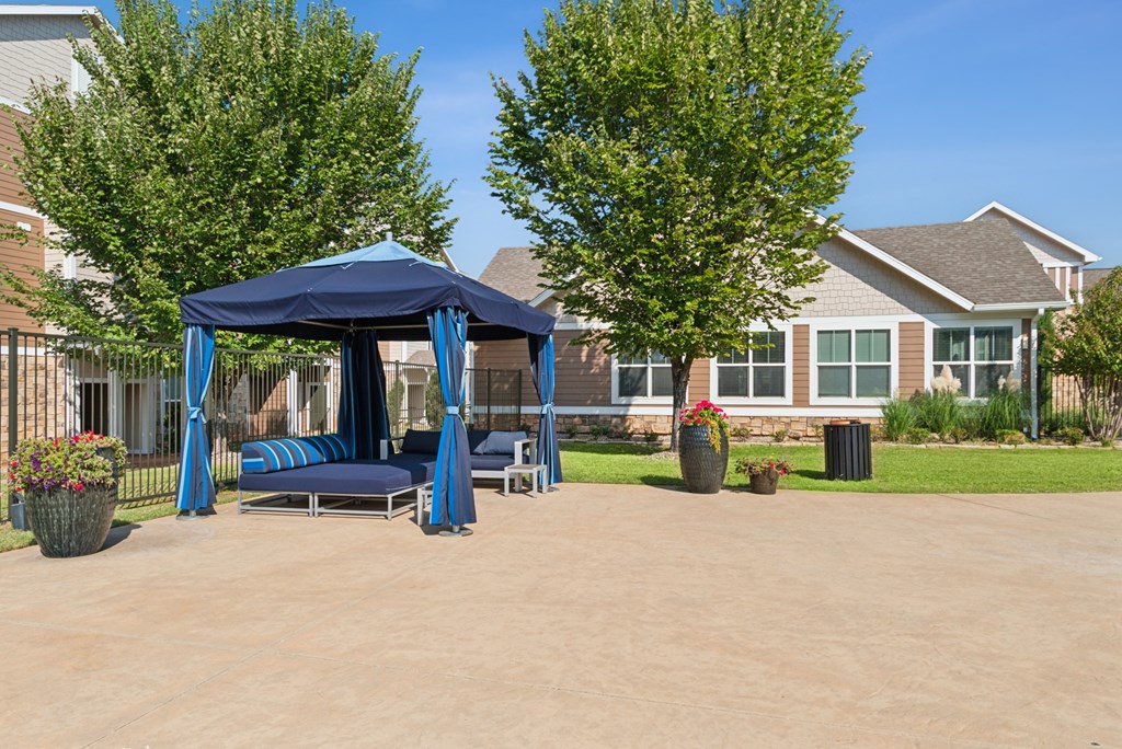 A blue canopy pavilion is situated in the middle of a paved area.