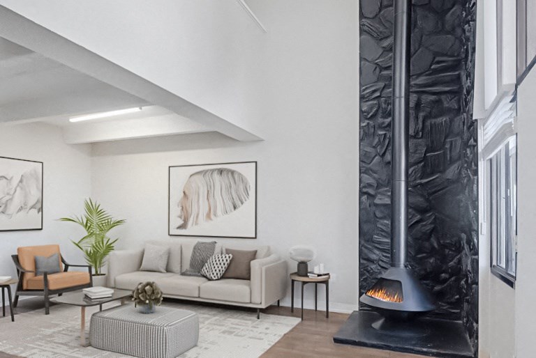 A modern living room with a grey sofa, a coffee table, a fireplace, and a painting on the wall.