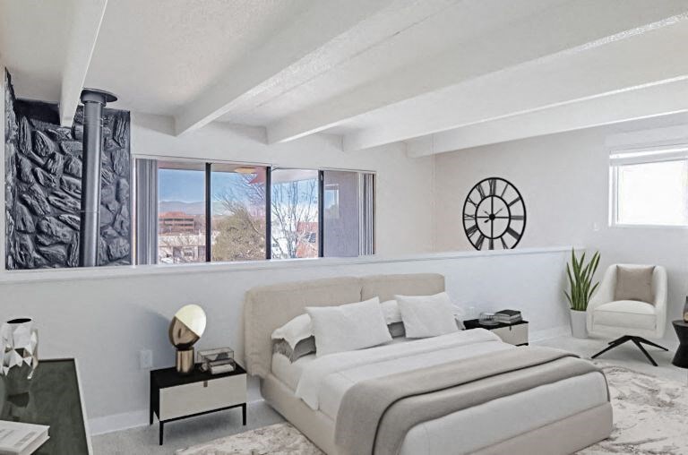 A bedroom with a large bed and a chair.