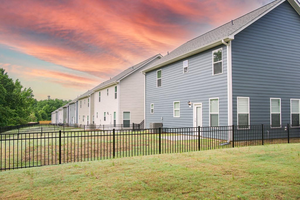 A line of houses with a black fence in front of them.