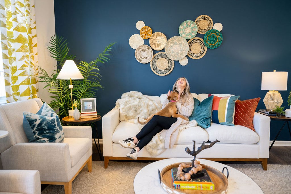 A woman is sitting on a white couch with a book in front of her.