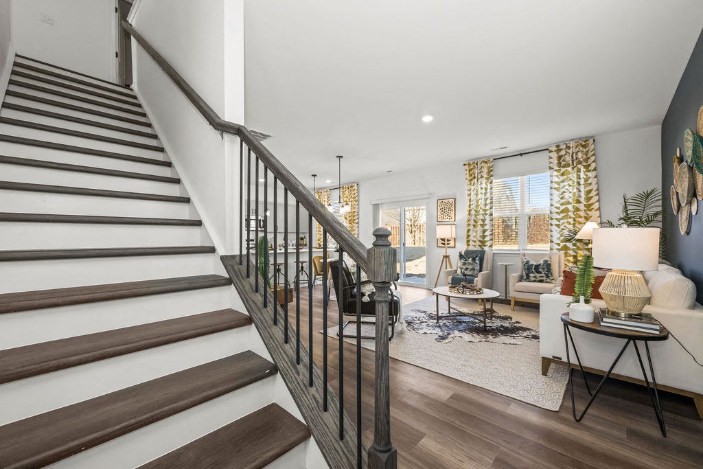 A staircase with a metal railing leads to a living room with a couch and a coffee table.