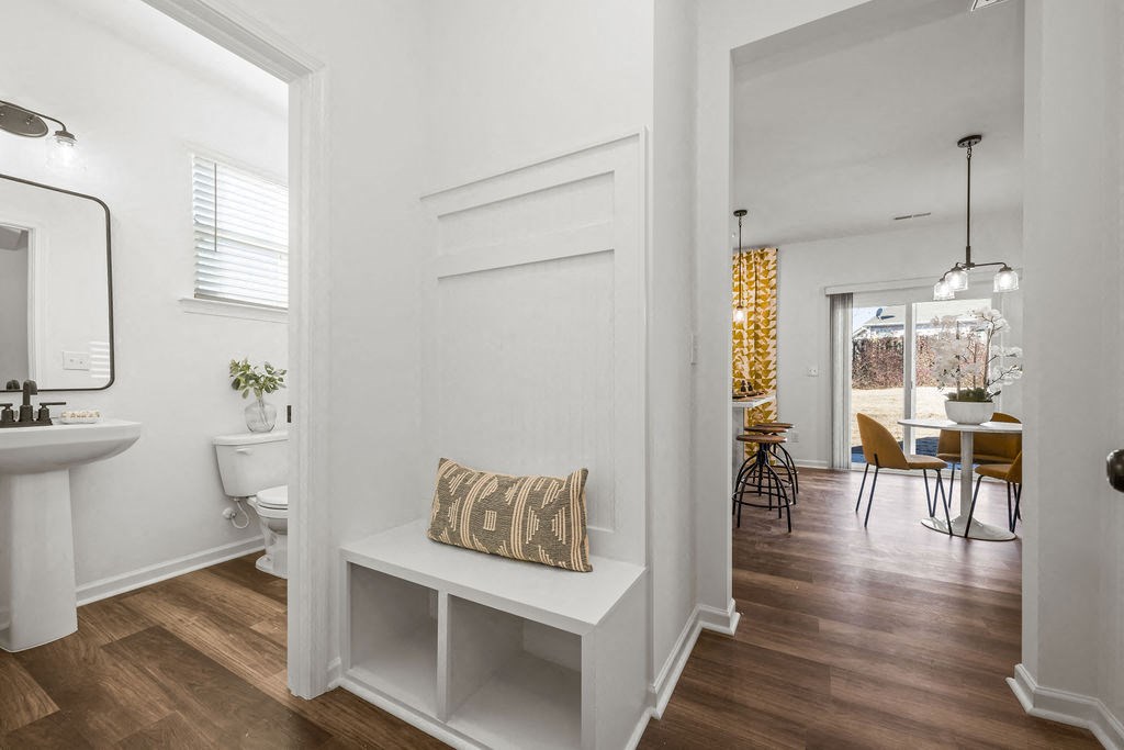 A white bathroom with a wooden floor and a white bench.