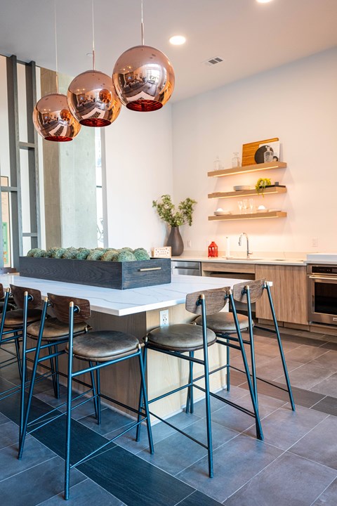 A modern kitchen with a white island and black chairs.