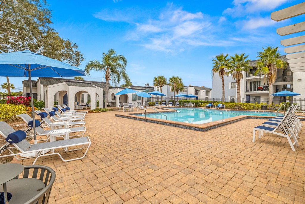 a resort style swimming pool with lounge chairs and umbrellas