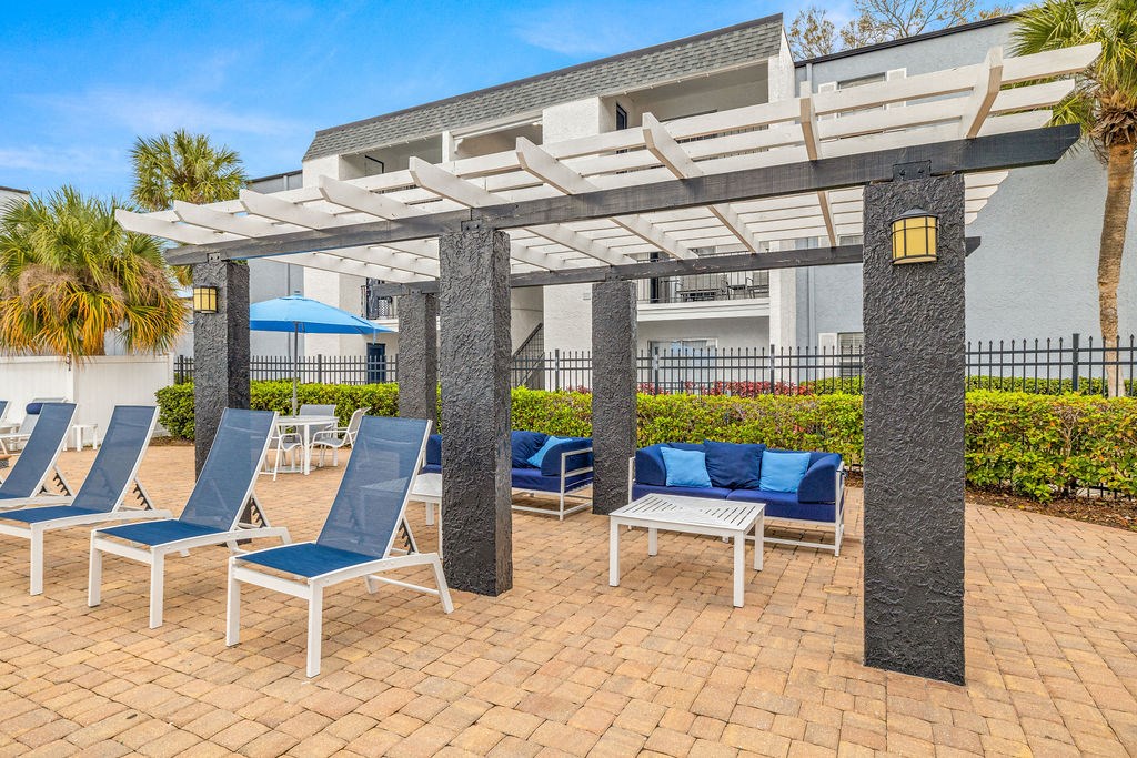 a patio with lounge chairs and a pergola