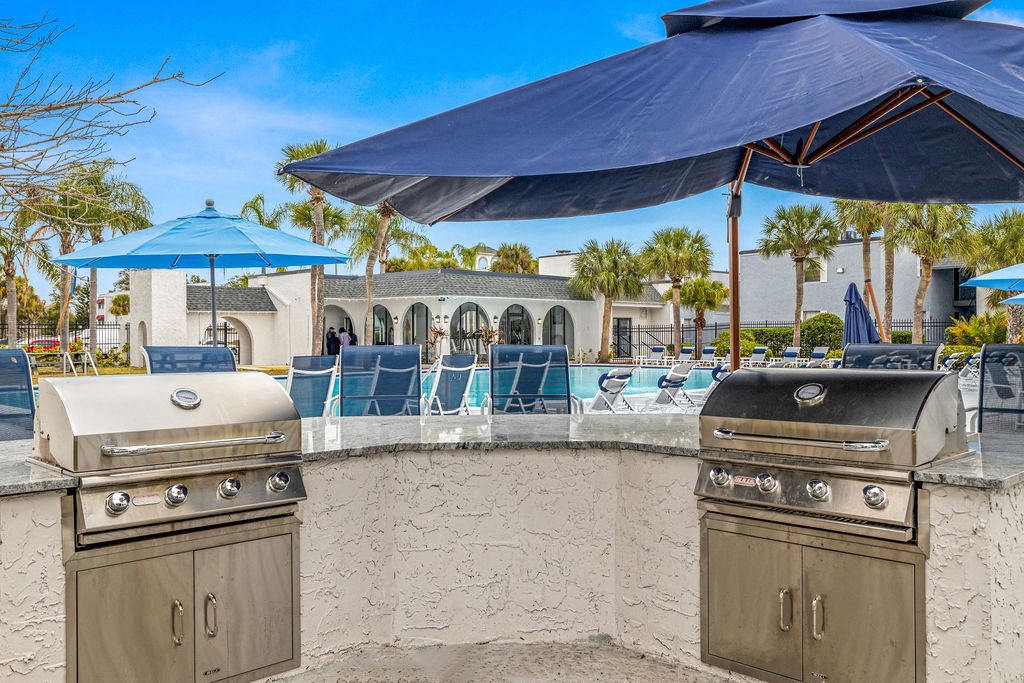 a resort style bar with barbecue grills and umbrellas