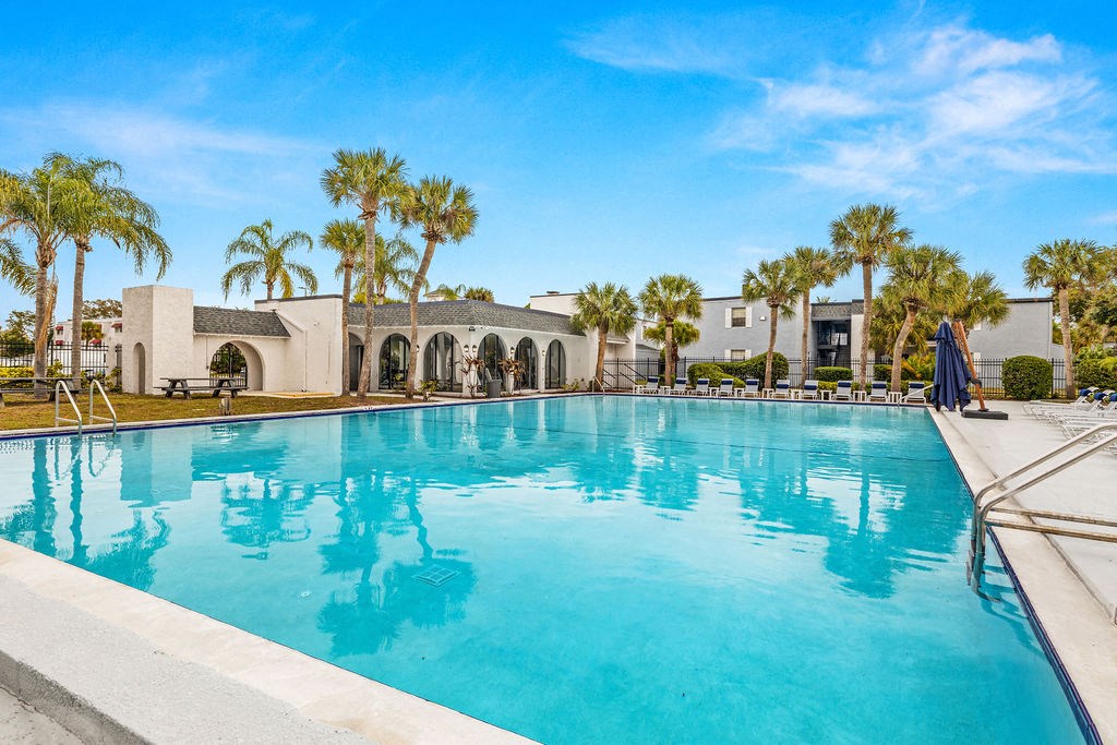 a large pool in front of a house with palm trees
