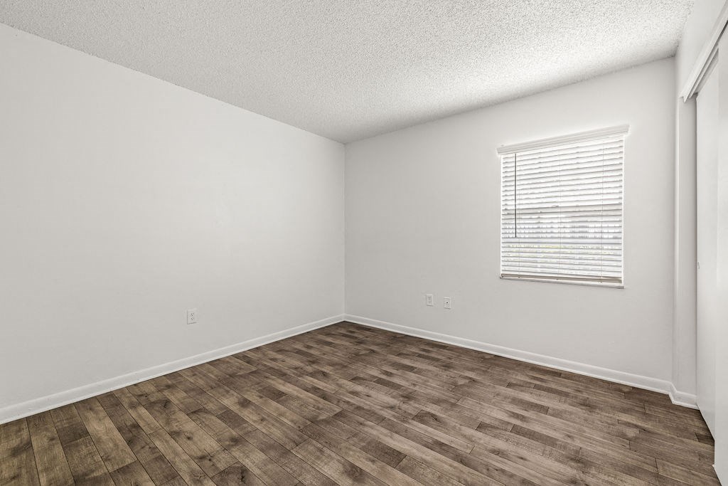 the spacious living room with wood flooring and a window