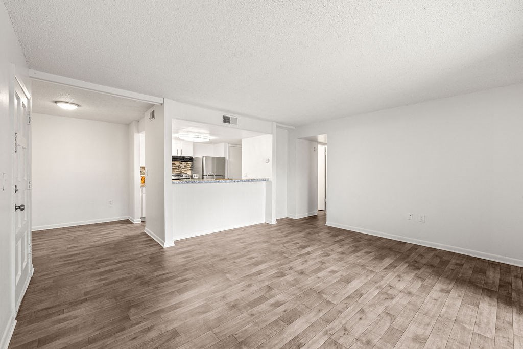 an empty living room and kitchen with wood flooring