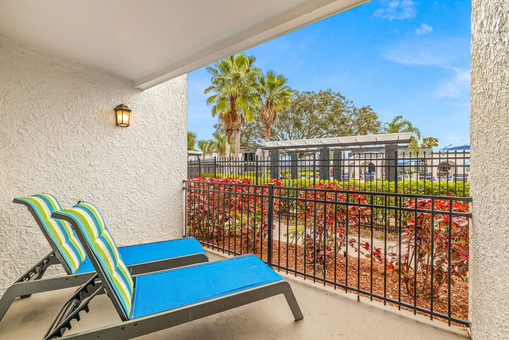 a balcony with two chairs and a view of a garden