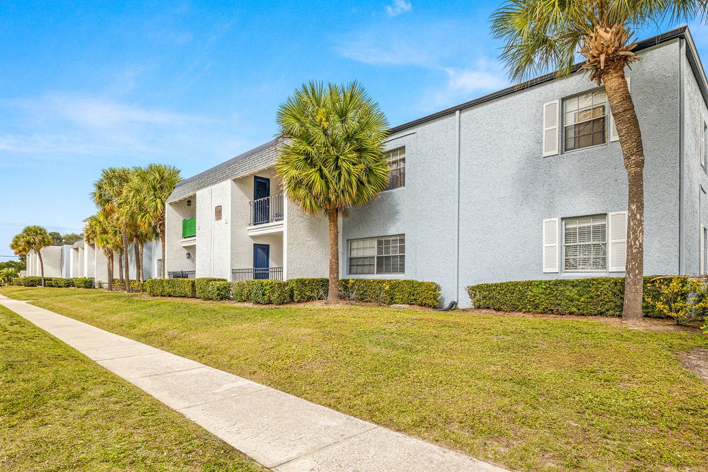 a white apartment building with palm trees in front of it