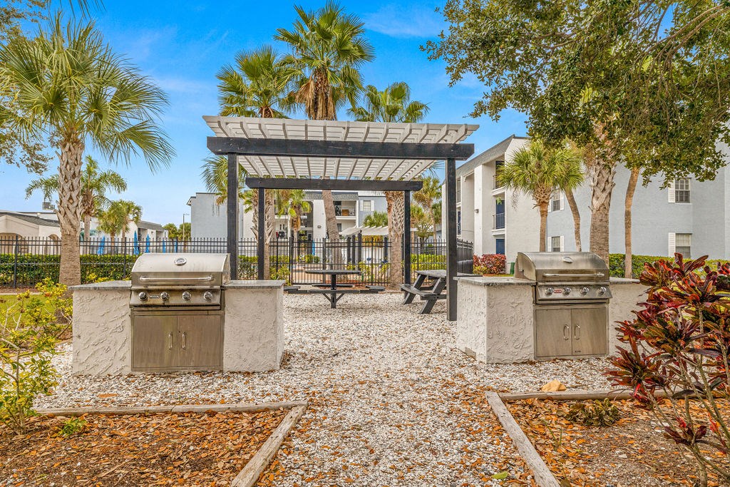 a picnic area with two bbqs and a gazebo with trees