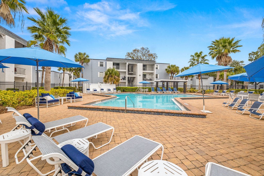 a swimming pool with lounge chairs and umbrellas