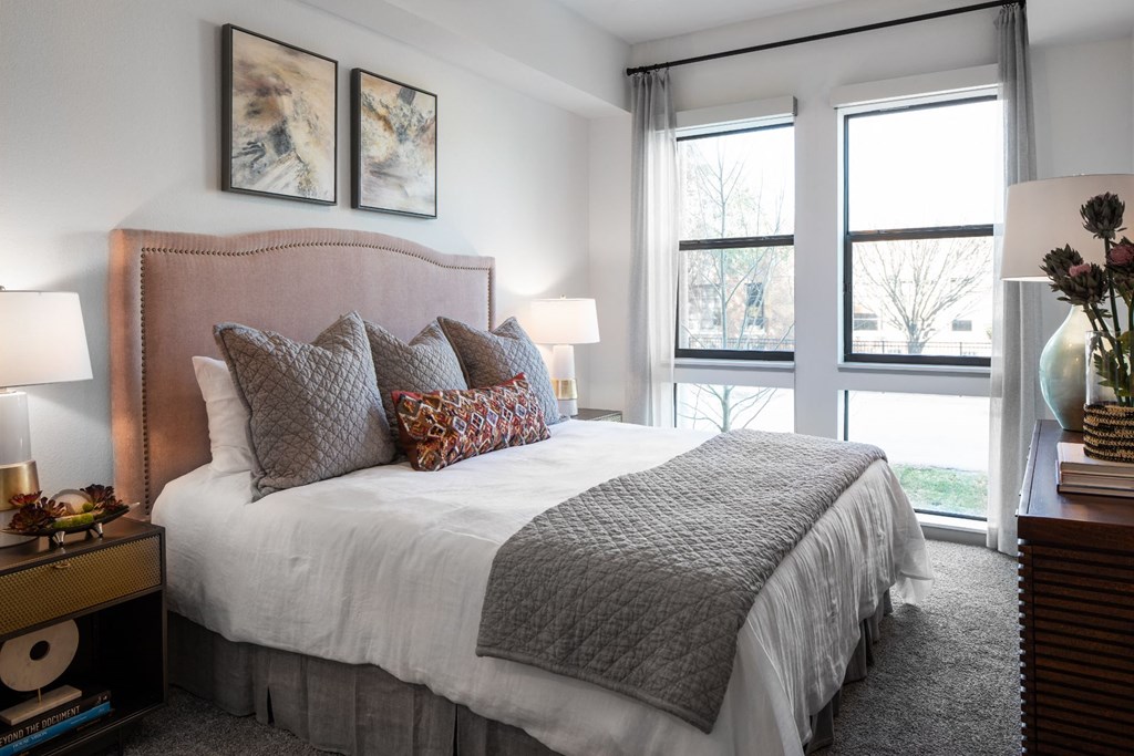 a bedroom with a large bed and two windows