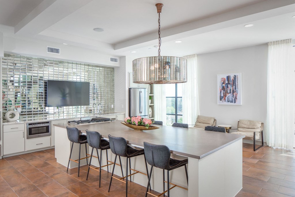 a kitchen with a large island with chairs and a tv