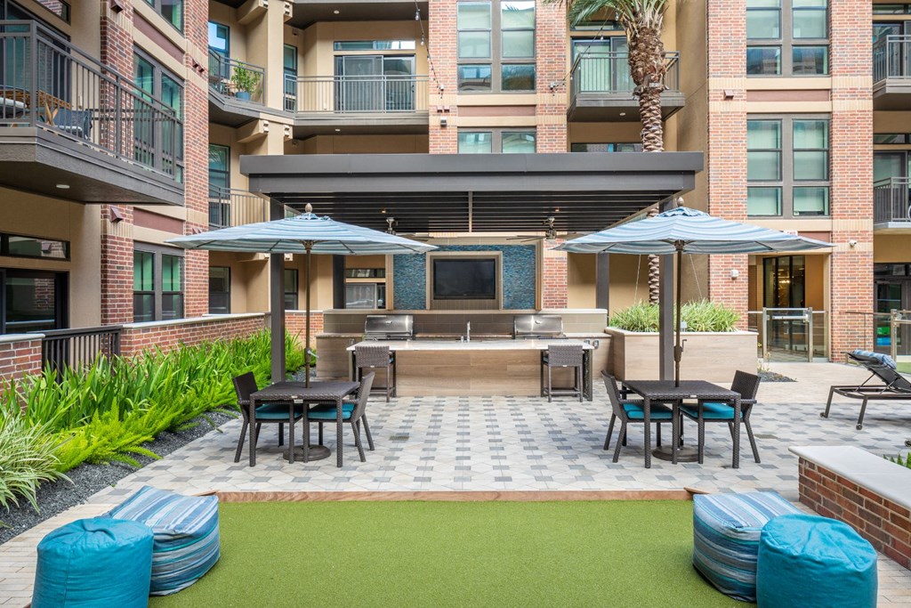 a patio with tables and umbrellas in front of an apartment building