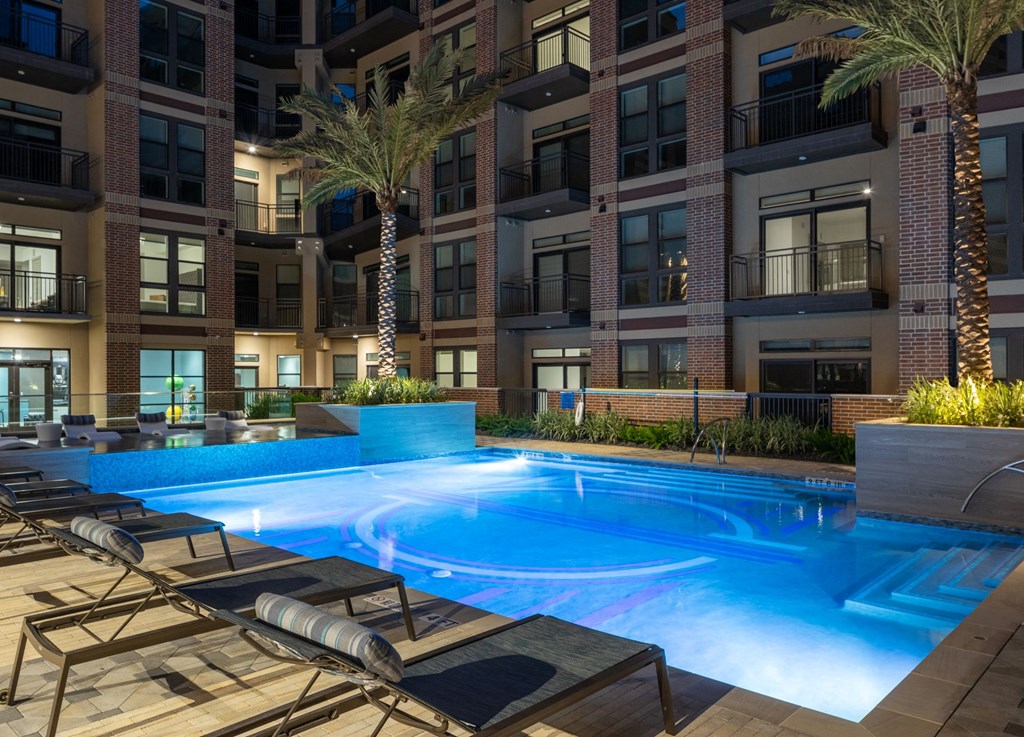 a swimming pool in front of a large apartment building