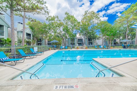 A swimming pool surrounded by trees and chairs with a 3 ft no diving sign.