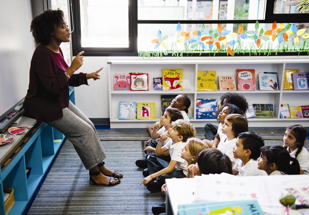 a teacher standing in front of a classroom of children