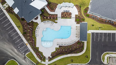 A large swimming pool surrounded by a grassy area and a building in the background.