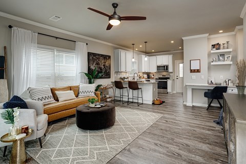 A modern living room with a white ceiling fan and a white rug on the floor.