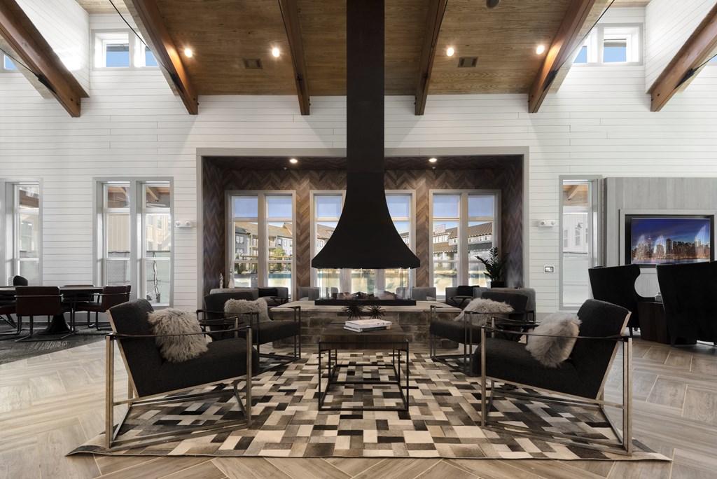 A modern living room with a black and white checkered rug and a large black fireplace.