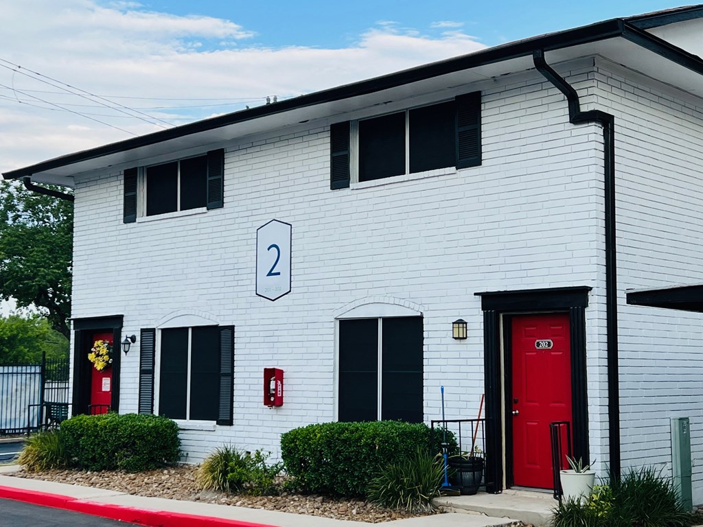 a white building with a red door and the number 2 on it