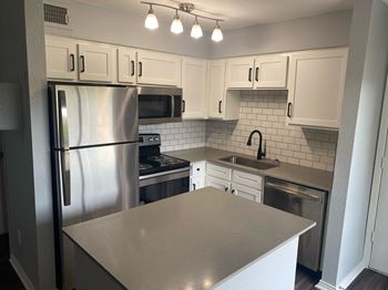 a kitchen with white cabinets and stainless steel appliances