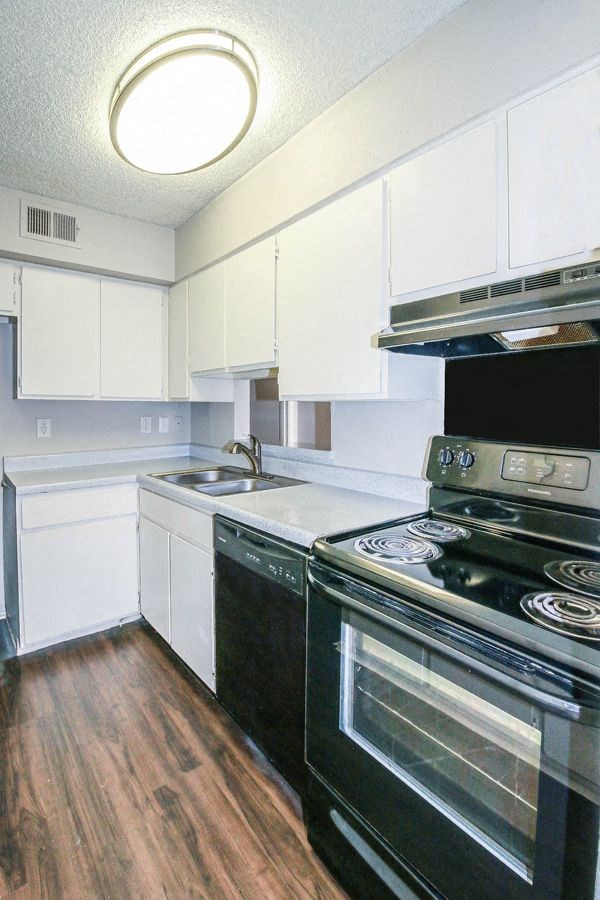 an empty kitchen with white cabinets and black appliances