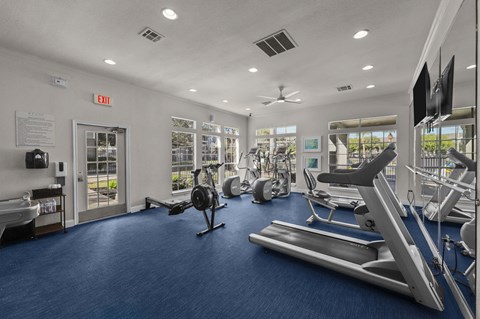 A gym with a variety of equipment including treadmills, exercise bikes, and weight machines.