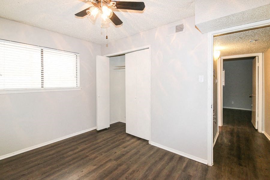 an empty living room with white walls and a ceiling fan