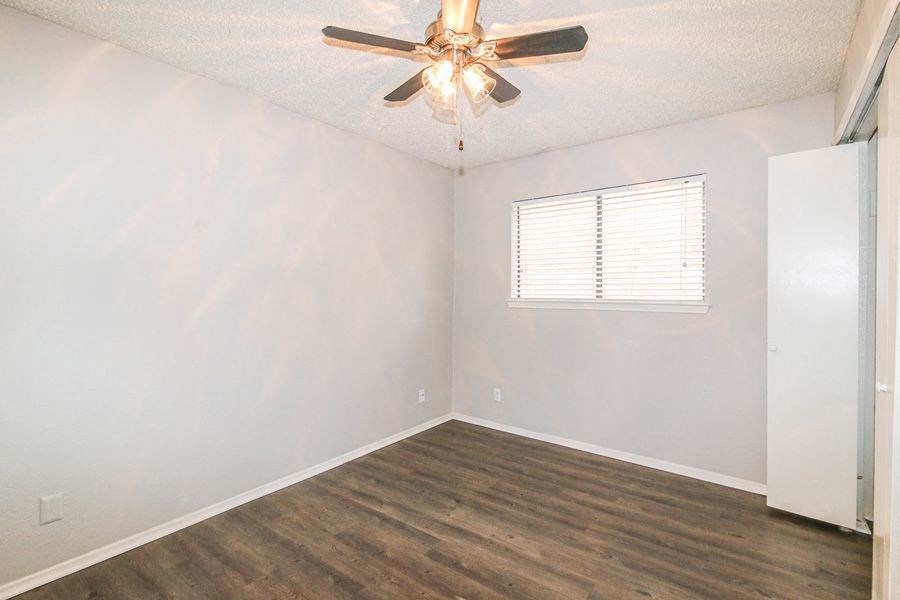 an empty bedroom with a ceiling fan and a window