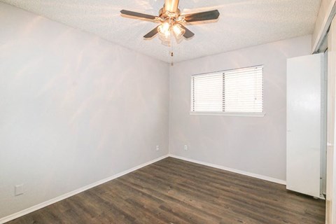 an empty bedroom with a ceiling fan and a window